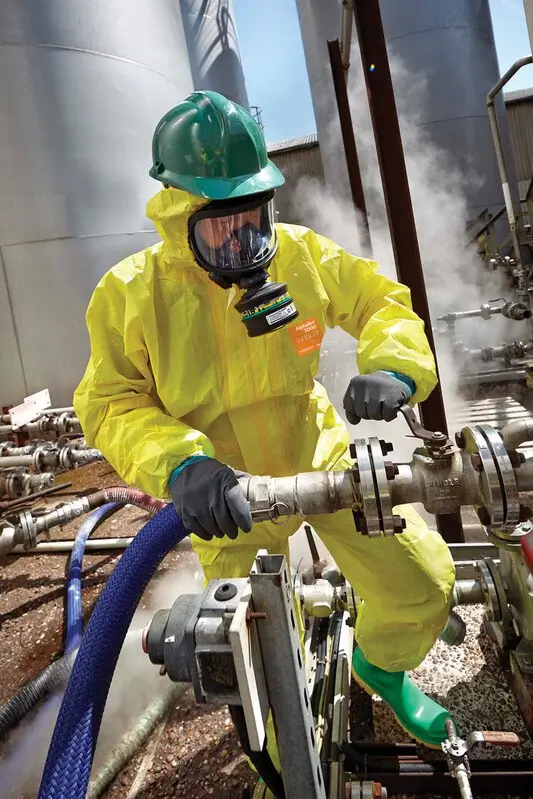 Trabajador con traje químico desechable industrial AlphaTec 3000 operando válvulas en una planta